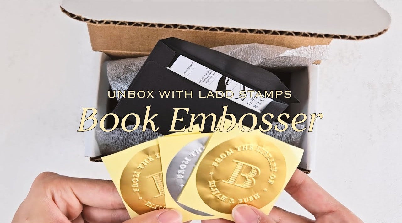 Book embosser with gold stamps and a box on a light background