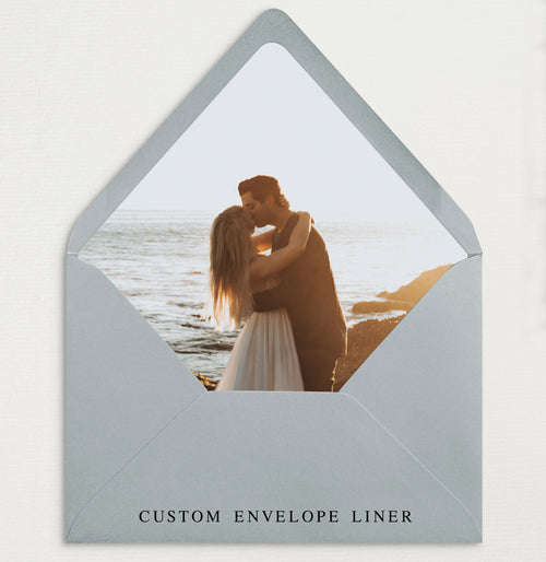 A custom envelope liner with a printed image of a couple embracing, set against a serene beach backdrop, with the text 'CUSTOM ENVELOPE LINER' at the bottom.