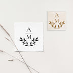 A personalized stamp with a laurel wreath design and the letter 'A' and 'M' in the center, displayed on a white background with a wood handle.